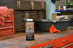 Spectro Oil bottle beside outdoor power tools showing reliable protection benefit