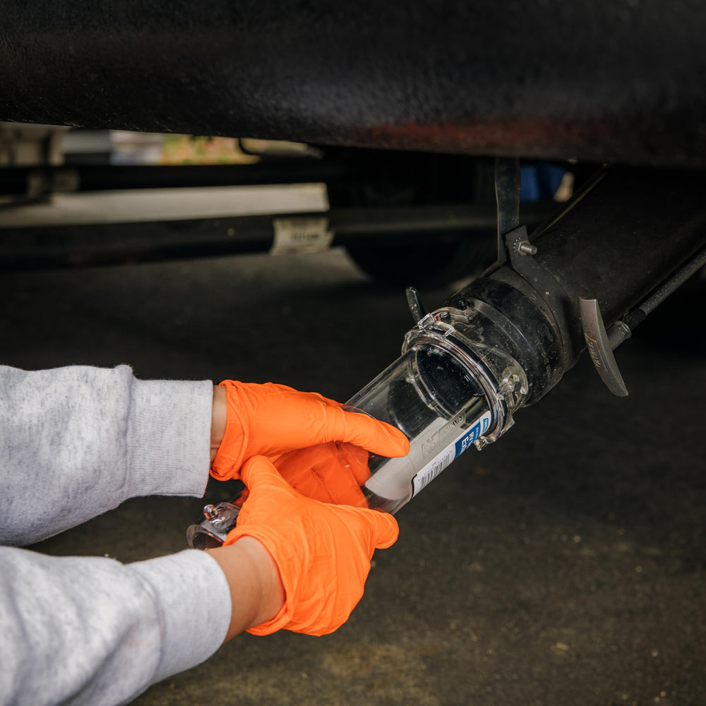 Camco adapter in use at dump station showing visible rinse flow benefit