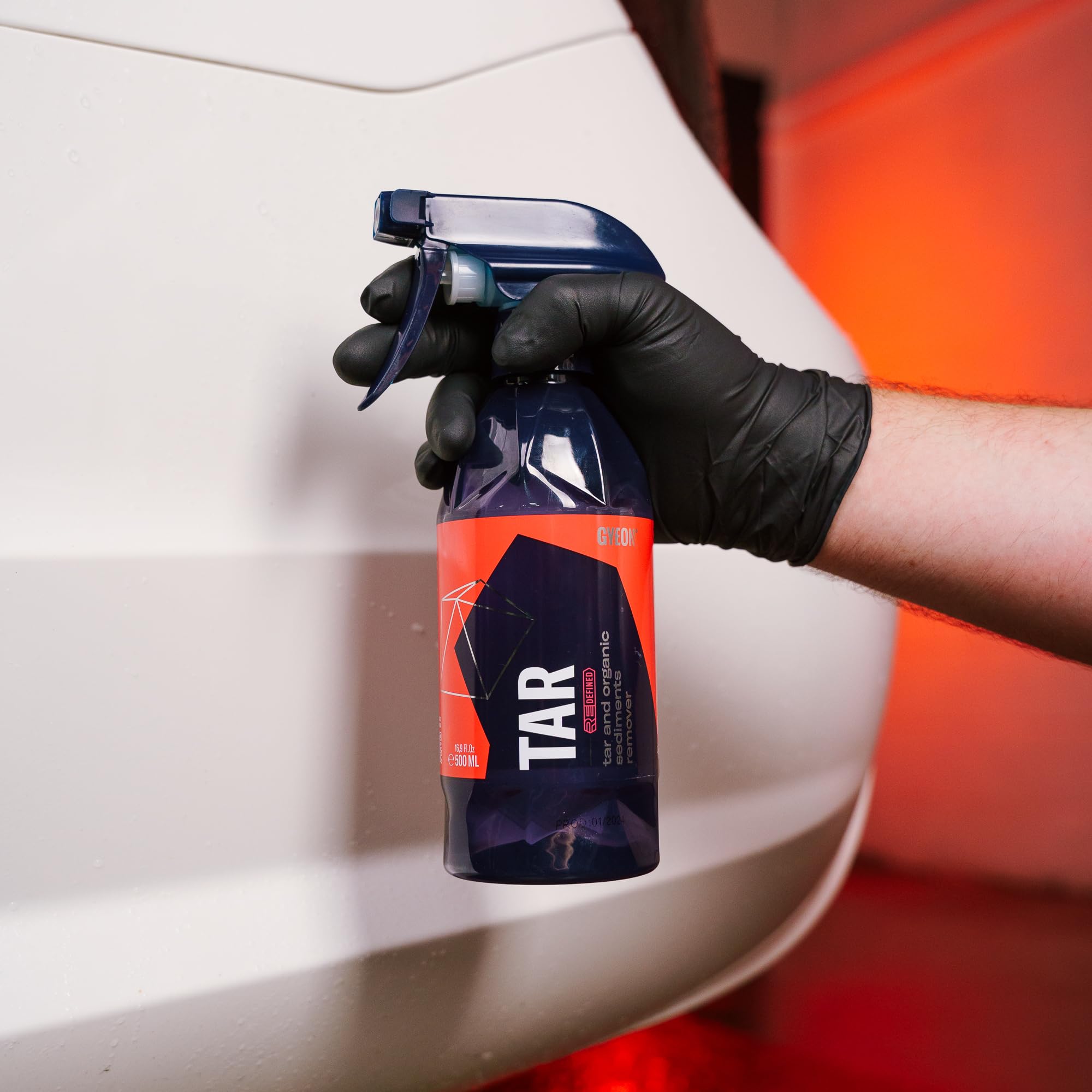 Gyeon tar remover being sprayed on car panel for fast tar breakdown
