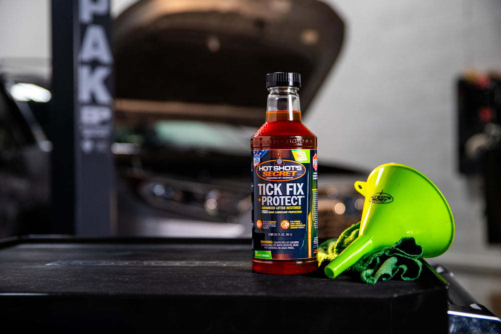 Hot Shot's Secret bottle near open car hood demonstrating in-vehicle use