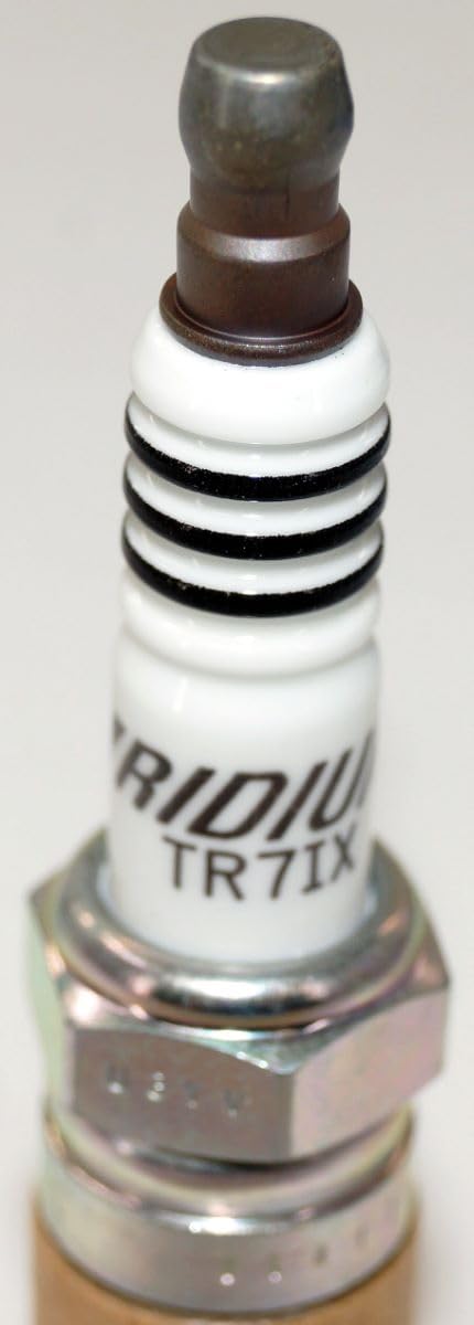 NGK Iridium IX plugs on a workbench in a garage setting suggesting professional use