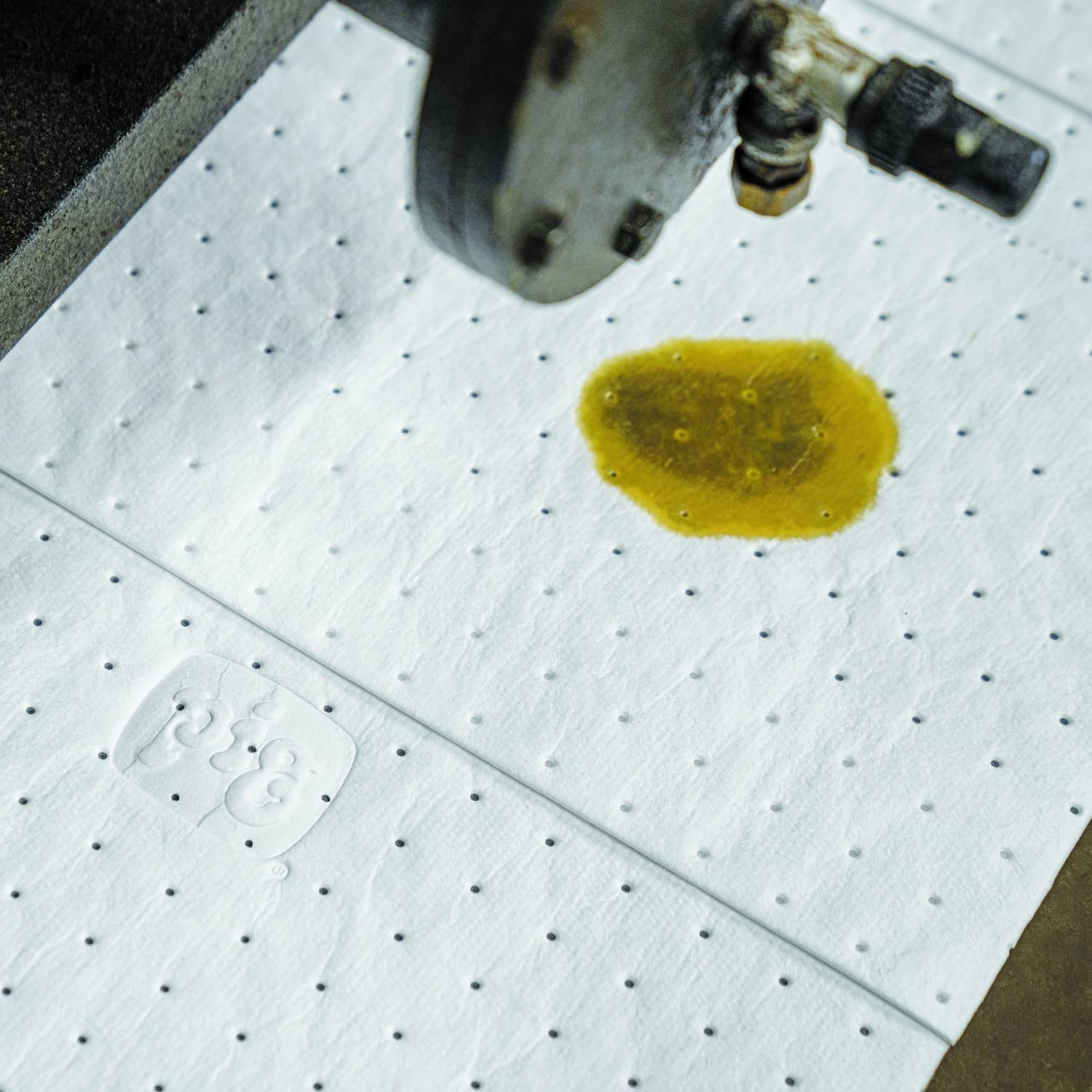 PIG pad absorbing motor oil in a garage for fast spill cleanup