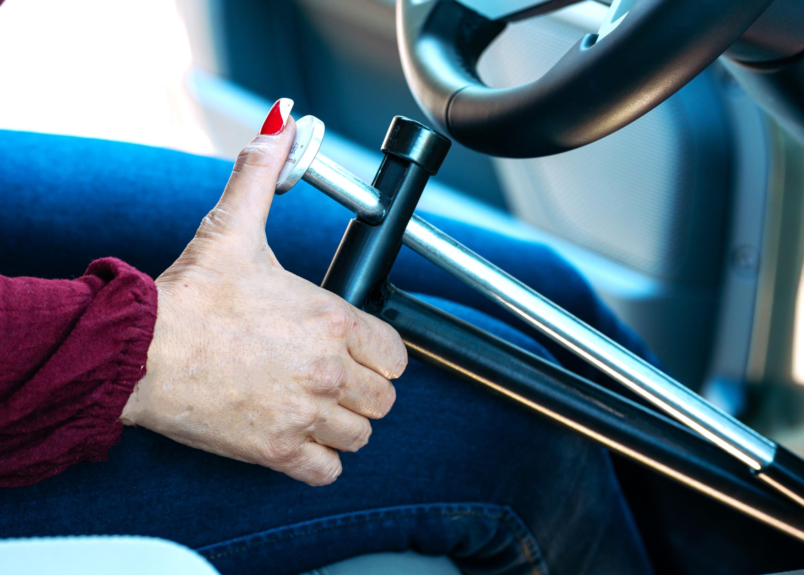 QuicStick size comparison next to steering wheel showing compact portability