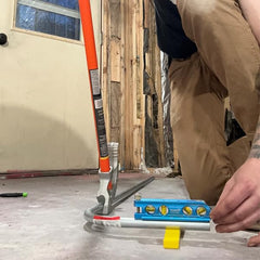 Rack-A-Tiers Kick Wedge placed under a 90-degree conduit elbow demonstrating accurate alignment