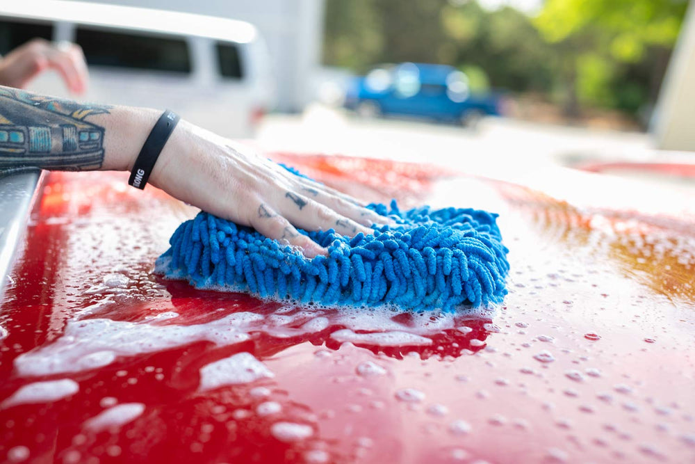 The Rag Company mitt in use washing a car door, demonstrating gentle cleaning