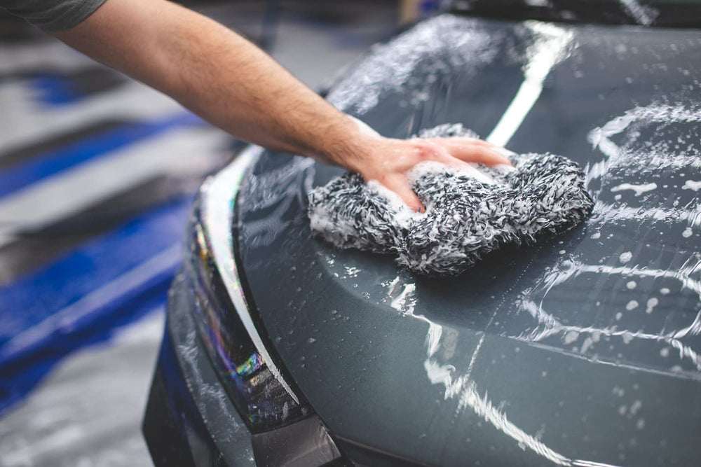 The Rag Company mitt gently gliding on car door showing scratch-free cleaning benefit