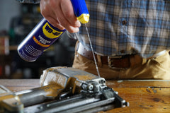 WD-40 Trigger Pro nozzle spraying lubricant onto hinge demonstrating controlled coverage