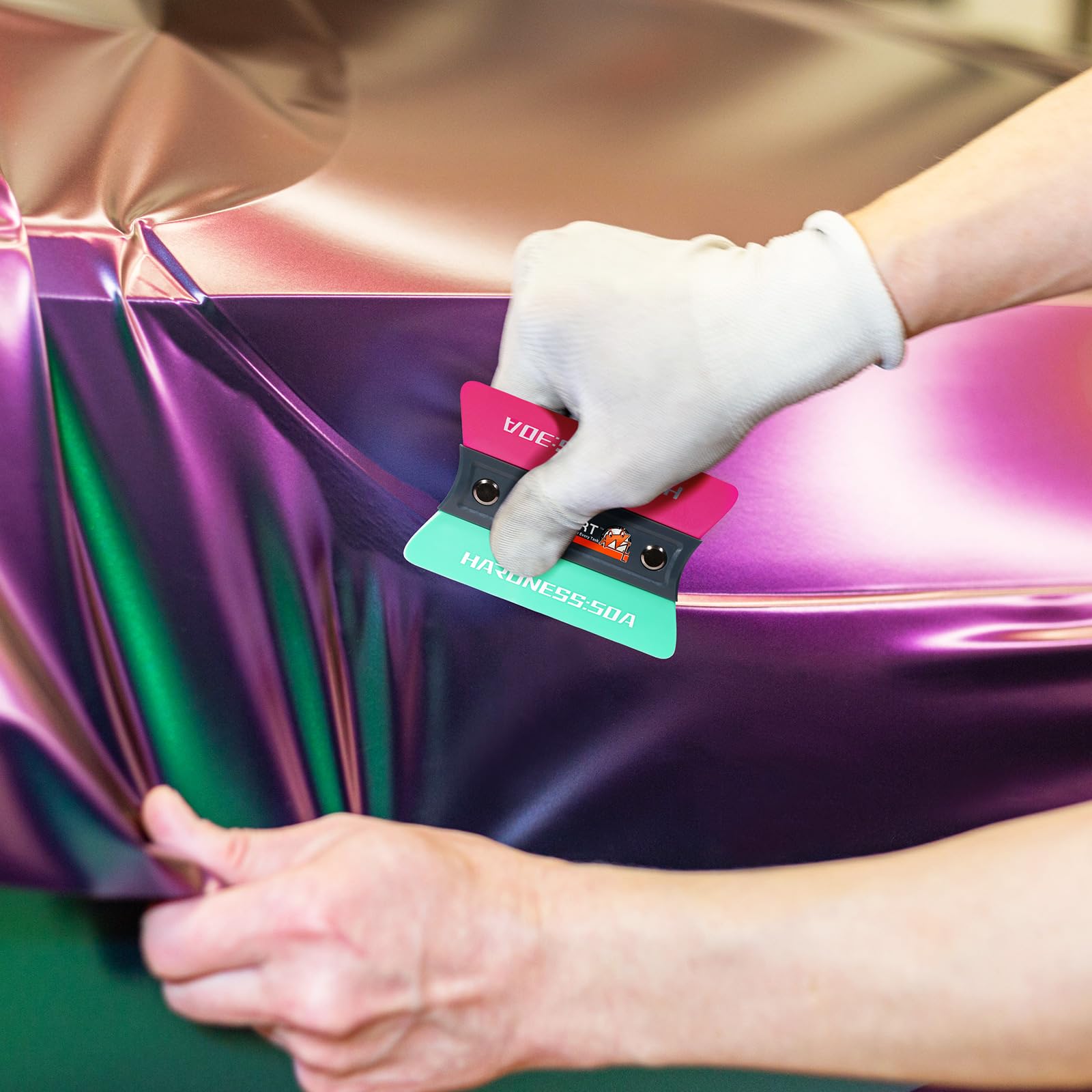 WRAPXPERT installer using the squeegee in a garage for efficient, professional-looking wraps